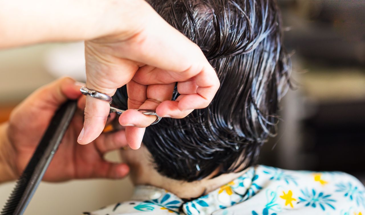 Mastering the First Impression: Your intriguing post title goes here Close-up of a hairstylist cutting short wet dark hair at a salon.